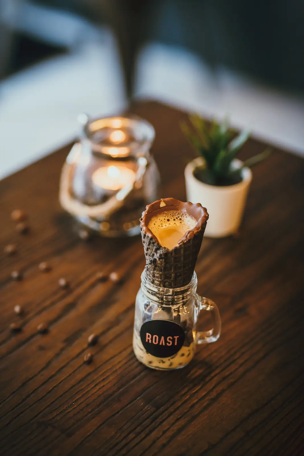 Drink served in a chocolate-coated cone on a small glass mug with a ROAST label, on a wooden table